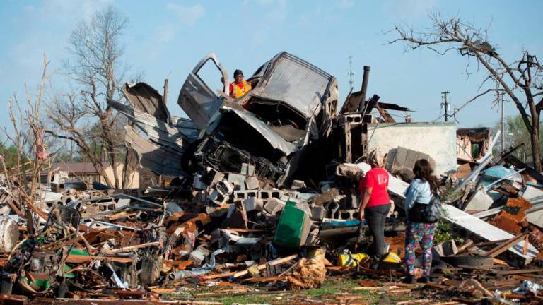 KeUntey Ousley tries to salvage what he can from his mother’s boyfriend’s vehicle, as his mother LaShata Ousley and his girlfriend Mikita Davis watch, after a tornado cut through their small Delta town the night before in Rolling Fork, Mississippi, U.S. March 25, 2023. REUTERSPIX