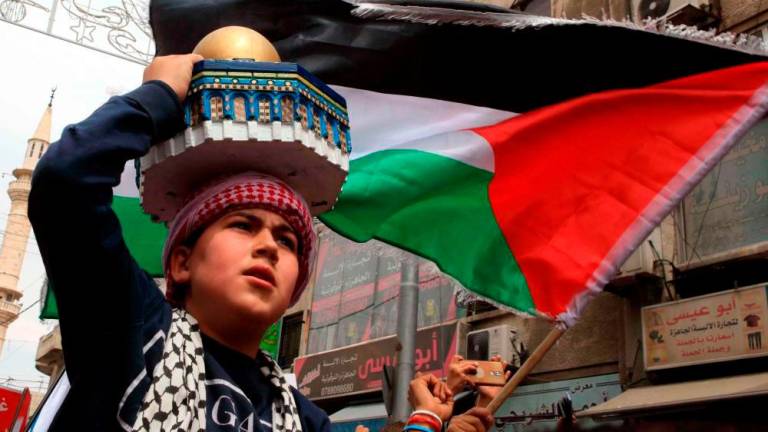 A young boy carries a replica of the Dome of the Rock mosque and waves a Palestinian flag as demonstrators march in the streets of the Jordanian capital Amman on April 22, 2022. AFPPIX