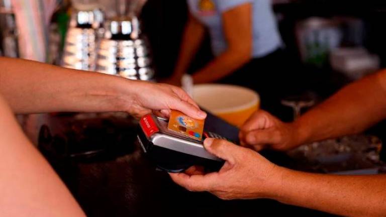 A woman pays with a credit card at a restaurant in Playa del Ingles, Maspalomas on the island of Gran Canaria, Spain, May 3, 2022. REUTERSPIX