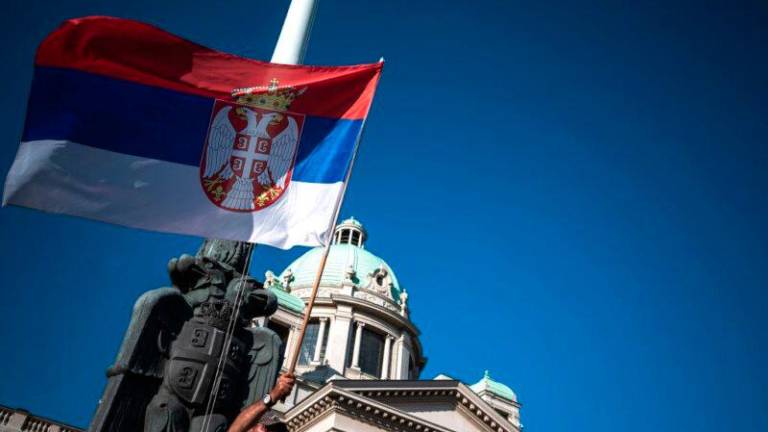 A man holds the Serbian national flag during a protest in front of the National assembly building in Belgrade on June 18, 2020. AFPPIX