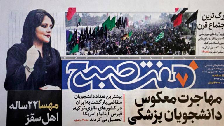 A picture taking in Tehran on September 18, 2022 shows the front page of the Iranian newspaper Hafteh Sobh featuring a photograph of Mahsa Amini, a woman who died after being arrested by the Islamic republic's morality police two days ago. - AFPPIX