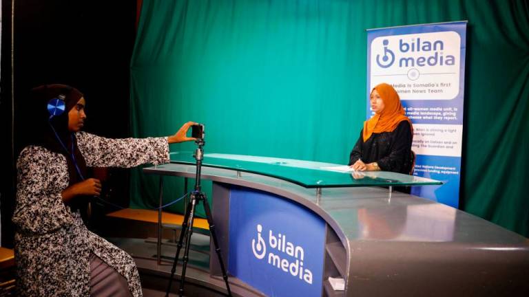 Shukri Mohamed Abdi and Fathi Mohamed Ahmed, journalists at Bilan Media, Somalia's first all-women media team, use a mobile to record the news inside the Bilan Media studios in Mogadishu, Somalia August 20, 2023. - REUTERSPIX