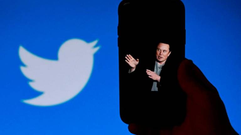 (FILES) In this file photo taken on October 04, 2022, an illustration photo shows a phone screen displaying a photo of Elon Musk with the Twitter logo shown in the background, in Washington, DC. - AFPPIX