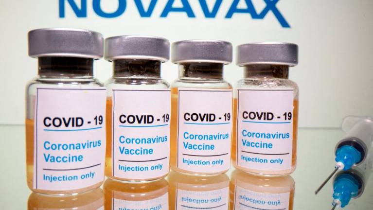 Vials of Covid-19 vaccine and a medical syringe are seen in front of a Novavax logo in this illustration. – Reuterspix