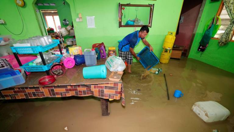 Flash flood victim Ehsan Sukardi, 50, cleaning out his things after water levels have gine down post flash flood at Kampung Baru Sengkang, Kulai on Nov 12 - BERNAMAPIX
