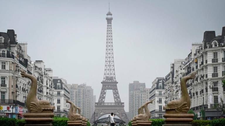 A man takes a picture of a tower modelled on the Eiffel Tower in Hangzhou, host city of the 2022 Asian Games, in China’s eastern Zhejiang province on September 22, 2023/AFPPix