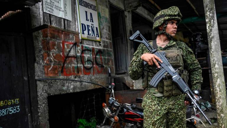 In this file photo taken on May 18, 2022, a Colombian soldier stands guard next to graffitis of the AGC Gaitanist Self-Defense Forces of Colombia or Clan del Golfo paramilitaries and the the ELN guerrillas at La Colonia village in the low Calima river region, near the port city of Buenaventura, Valle del Cauca department/AFPPix