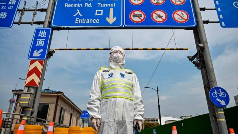 (FILES) In this file photo taken on March 28, 2022, a transit officer wearing protective gear controls access to a tunnel in the direction of the Pudong district in Shanghai under lockdown as a measure against the Covid-19 coronavirus. AFPPIX