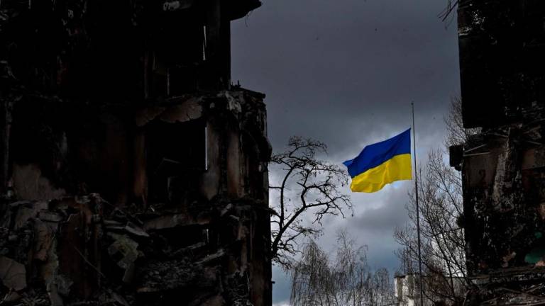 The Ukrainian flag flutters between buildings destroyed in bombardment, in the Ukrainian town of Borodianka, in the Kyiv region on April 17, 2022. Russia invaded Ukraine on February 24, 2022. AFPPIX