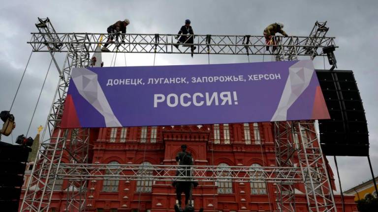 Workers fix a banner reading “Donetsk, Lugansk, Zaporizhzhia, Kherson - Russia!” on top of a construction installed in front of the State Historical Museum outside Red Square in central Moscow on September 29, 2022. Russia will formally annex four regions of Ukraine its troops occupy at a grand ceremony in Moscow on September 30, the Kremlin has announced, after it suggested using nuclear weapons to defend the territories. AFPPIX