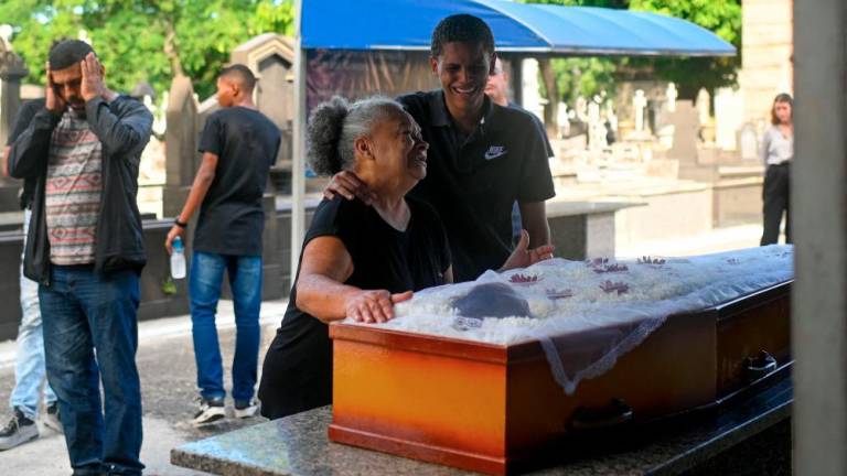 Divone Ferreira, mother of Gabrielle Ferreira da Cunha, 41, who was killed by a stray bullet while being inside her house during a police operation in a neighbouring favela, cries next to her daughter's coffin at the Sao Francisco Xavier Cemetery in Rio de Janeiro, Brazil, on May 25, 2022. AFPPIX