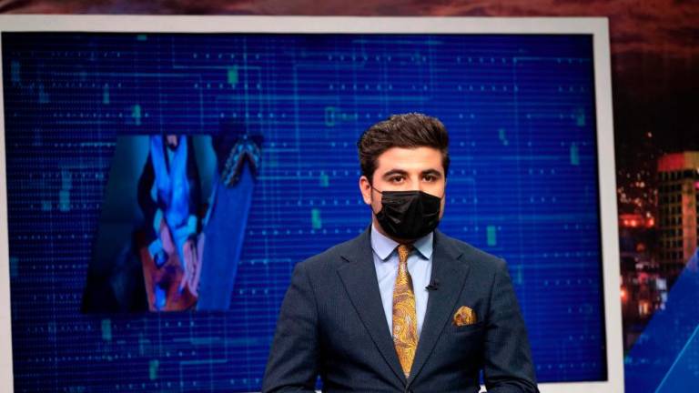 Seconds before he presents a news bulletin, Afghan television anchor Nisar Nabil puts on a black mask as a symbolic protest against the Taliban authorities for ordering women presenters to cover their faces on air. AFPPIX