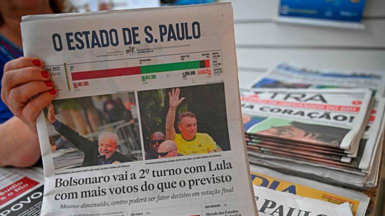 A vendor holds up the front page of one of Brazil’s National newspapers the day after the Presidential elections in Rio de Janeiro, Brazil on October 3, 2022. AFPPIX