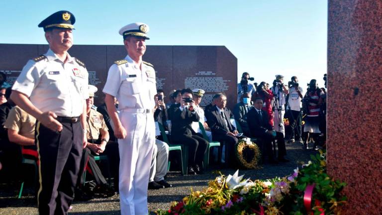 This picture taken on August 7, 2022, shows Japan's Chief of Staff, Joint Staff General Koji Yamazaki (L) paying his respects during a ceremony marking the 80th anniversary of the Battle of Guadalcanal at Skyline Ridge in Honiara on the Solomon Islands. A man described as mentally affected injured a Japanese sailor during a World War II memorial ceremony in Solomon Islands on August 8, before bystanders, including military personnel, overpowered him. - AFPPIX
