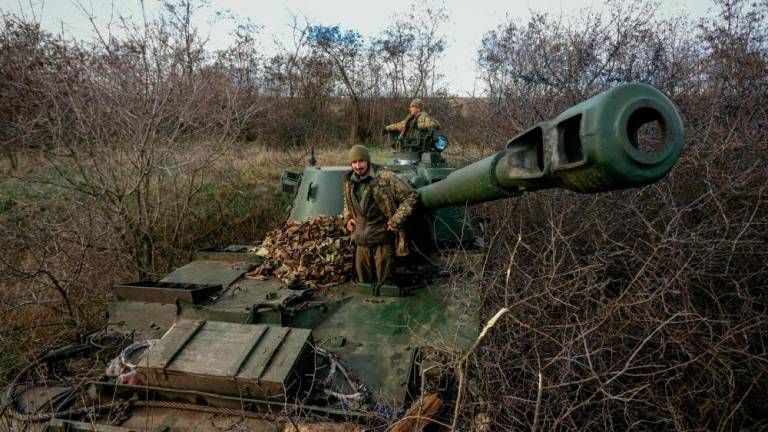 This photograph taken on November 30, 2022 shows Ukrainian artillerymen standing atop their 2S3 Akatsiya (Self propelled howitzer) in a field near an undisclosed frontline position in eastern Ukraine, amid the Russian invasion of Ukraine. AFPPIX