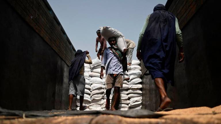 Workers carry sacks of wheat to load on a freight train at Chawa Pail railway station in Khanna, Punjab state, on May 19, 2022. AFPPIX