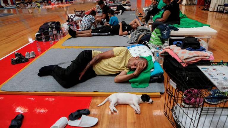 A man and his dog find shelter in an indoor stadium after being evacuated from flooded areas, in the aftermath of Storm Daniel, in Larissa, Greece, September 10, 2023. REUTERSPIX