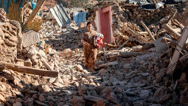 TOPSHOT - A woman walks past destroyed houses after an earthquake in the mountain village of Tafeghaghte, southwest of the city of Marrakesh//AFPix