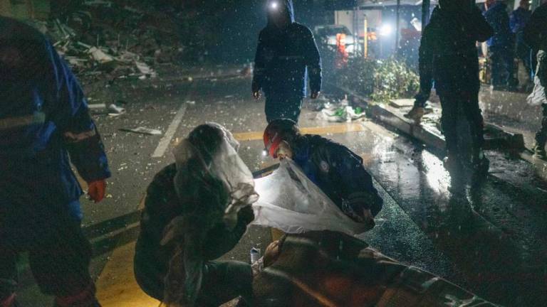Pekerja penyelamat membantu seorang yang cedera di sebelah runtuhan di Hatay pada 6 Februari 2023, selepas gempa bumi berukuran 7.8 magnitud melanda tenggara negara itu. fotoAFP