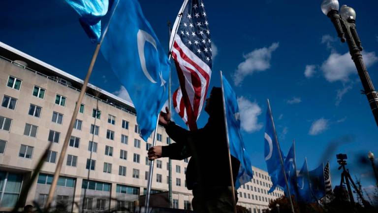A man holds an American flag next to East Turkmenistan flags while protesting the treatment of Uyghur by China as well as deaths associated with the recent Urumchi fire during a rally outside the US Department of State November 28, 2022, in Washington, DC. AFPPIX