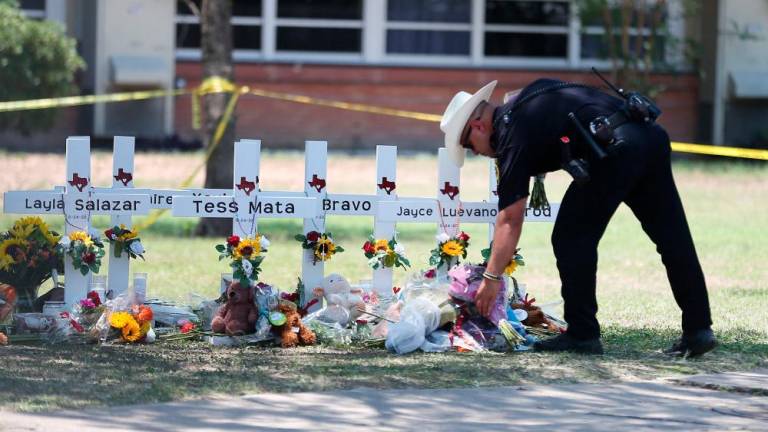 A police officer sets flowers from someone mourning at a memorial at Robb Elementary School days after a mass shooting in Uvalde, Texas, U.S., May 26, 2022. Briana Sanchez/American-Statesman/USA Today Network via REUTERSpix