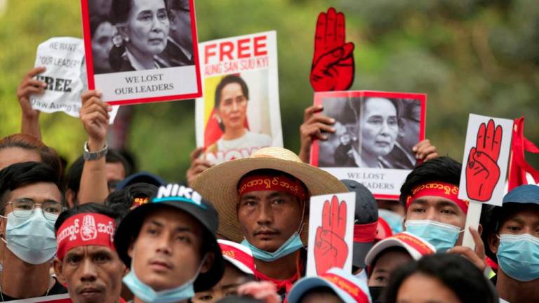 FILE PHOTO: Demonstrators hold placards with pictures of Aung San Suu Kyi as they protest against the military coup in Yangon, Myanmar, February 22, 2021. - REUTERSPIX