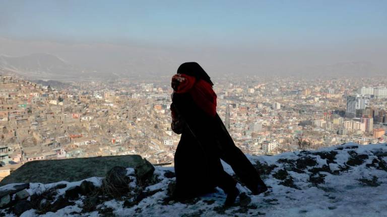 An Afghan woman holds her child as she walks on a snow-covered street on the TV mountain in Kabul, Afghanistan/ REUTERSPIC