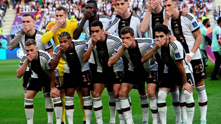 Players of Germany cover their mouths as they pose for the group picture ahead of the Qatar 2022 World Cup Group E football match between Germany and Japan at the Khalifa International Stadium in Doha on November 23, 2022. - AFPPIX