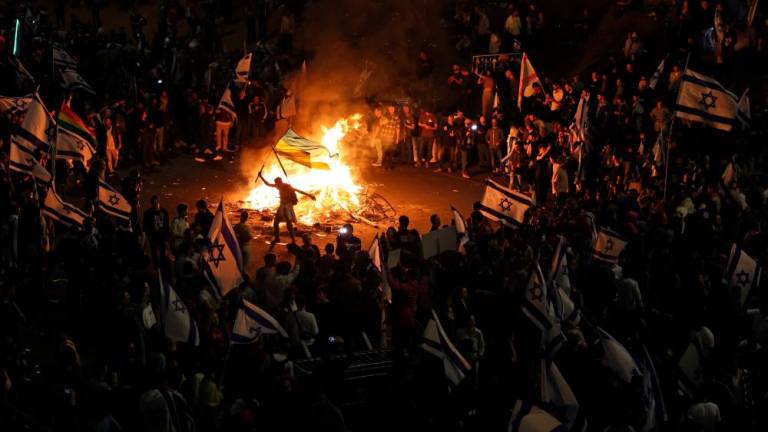 Protesters block a road and hold national flags as they gather around a bonfire during a rally against the Israeli government’s judicial reform in Tel Aviv, Israel on March 27, 2023. AFPPIX