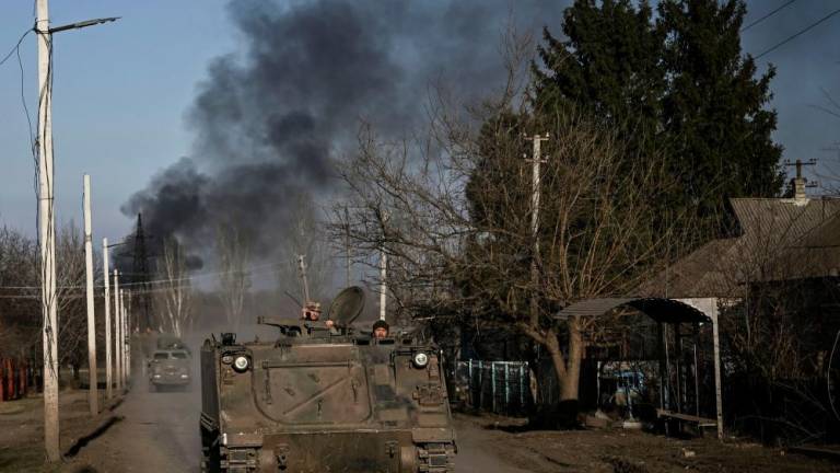 Ukrainian servicemen with a M113 armoured personnel carrier drive in the town of Chasiv Yar as smoke rises from the direction of Bakhmut on March 20, 2023. AFPPIX