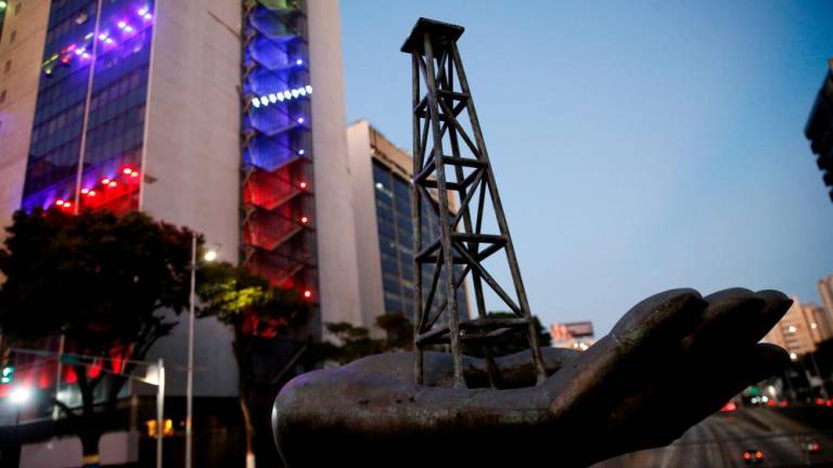 A sculpture depicting an oil tower on a hand of Venezuela’s state oil company PDVSA is pictured near the company’s headquarters, in Caracas on March 20, 2023. – Reuterspic