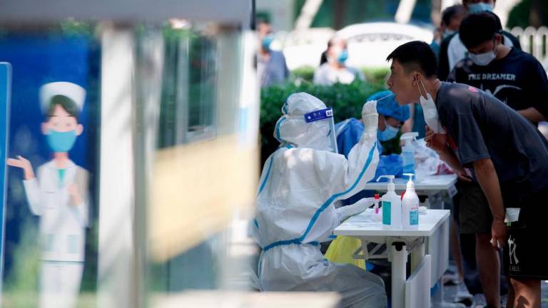 A health worker takes a swab sample from a man to be tested for the Covid-19 coronavirus at a swab collection site in Beijing on May 23, 2022. AFPpix