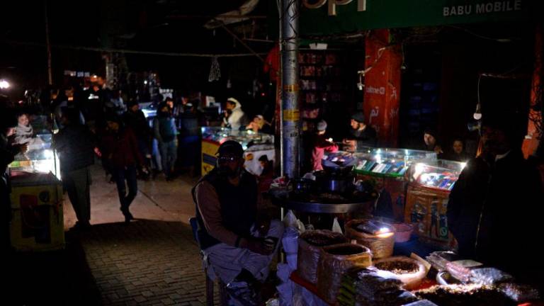 Shopkeepers sit at a market during a nationwide power outage, in Islamabad on January 23, 2023. AFPPIX