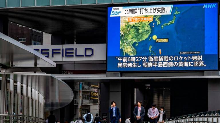 Pedestrians walk past a large video screen showing a map of the region during a news update in Tokyo on May 31, 2023, after North Korea launched a spy satellite that crashed into the sea/AFPPix