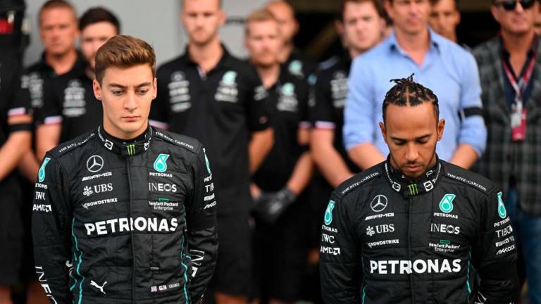 Mercedes’ British driver Lewis Hamilton (R) and Mercedes’ British driver George Russell (L) observe a moment of silence in the pit lane one day after the death of Britain’s Queen Elizabeth II before the first practice session ahead of the Italian Formula One Grand Prix at the Autodromo Nazionale circuit in Monza on September 9, 2022. AFPPIX