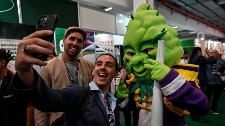 A visitor takes a selfie picture with a person in a costume of a cola of a cannabis plant during the Cannabis Expo Brazil, a hemp and cannabis industry exhibition, in Sao Paulo, Brazil, on September 15, 2023. AFPPIX