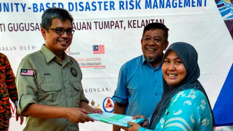 TUMPAT, July 31 -- Deputy Director General of the Post Disaster Management Division, National Disaster Management Agency (Nadma), Datuk Khairul Shahril Idrus (left) presenting a certificate to resident representative Nik Fazilah Mohd Nawi (right) at the Community Based Disaster Risk Management Program Organized by Petronas and the National Disaster Management Association (NADIM) in Teluk Renjuna today. BERNAMAPIX