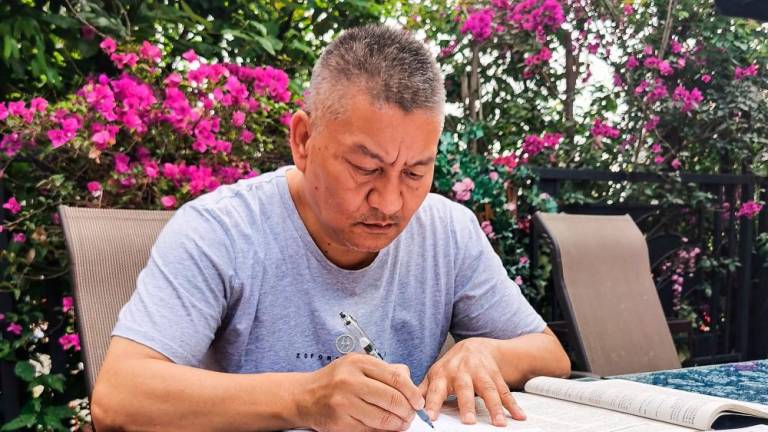 This handout picture taken on May 25 and released to AFP by Liang Shi on June 6, 2023 shows Liang Shi, a fifty-six-year-old man who sat Gaokao for the 27th time this year, going through exam papers ahead of the exam in Chengdu, in China’s southwestern Sichuan province. AFPPIX
