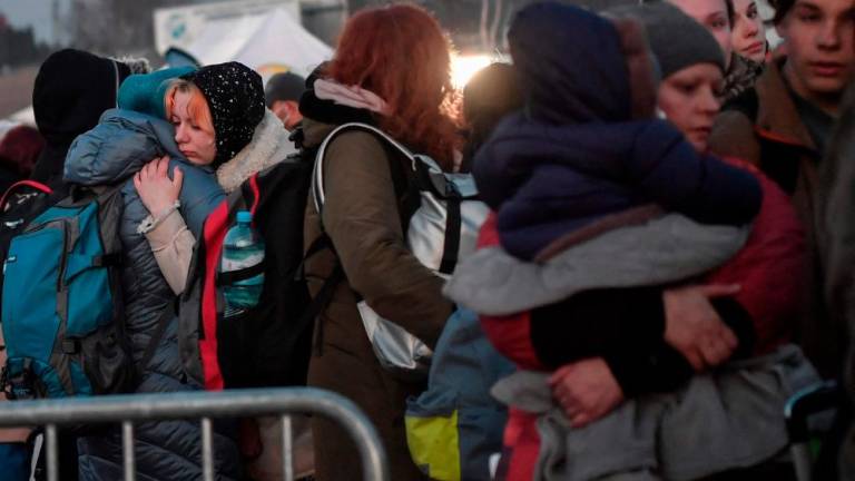 (FILES) Women hug as refugees queue for further transport after crossing the Ukrainian border with Poland in Medyka, southeastern Poland on March 14, 2022. AFPPIX