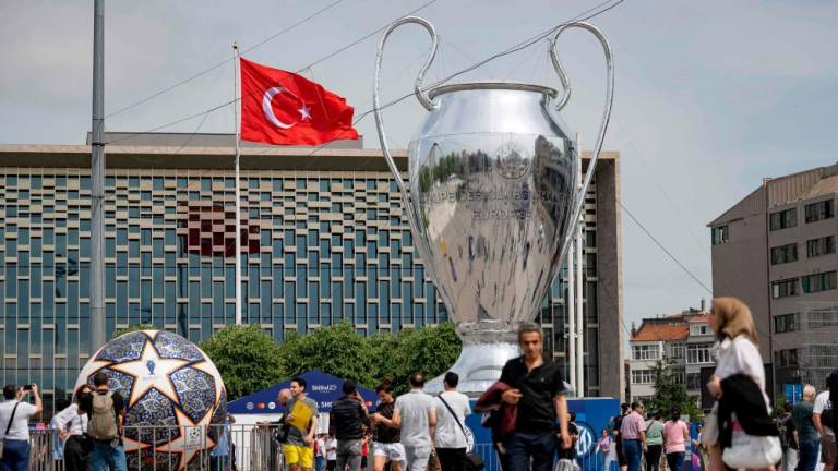 Pedestrians walk an inflatable model of the UEFA Champions League trophy on Taksim Square in Istanbul, on June 2023. AFPPIX