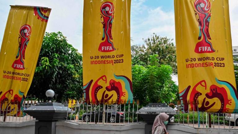 A woman walks past banners for the Indonesia 2023 FIFA Under-20 World Cup football tournament in Jakarta on March 30, 2023. AFPPIX