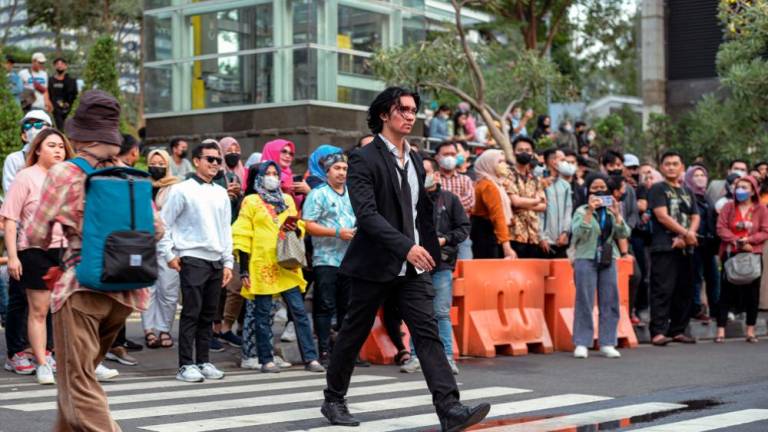 This picture taken on July 22, 2022 shows Indonesian youths presenting self-styled fashion creations at a pedestrian crossing turned catwalk, part of a gathering in recent weeks dubbed “Citayam Fashion Week”, in Jakarta. AFPPIX