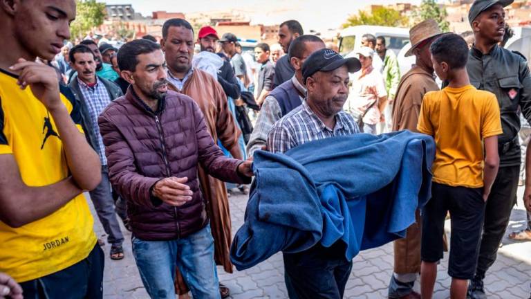 A man carries the blanket-wrapped body of a victim killed in an earthquake in Moulay Brahim, Al Haouz province, on September 9, 2023. AFPPIX