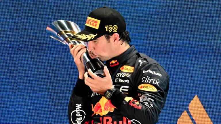 TOPSHOT - Winner Red Bull Racing's Mexican driver Sergio Perez celebrates on the podium after the Formula One Singapore Grand Prix night race at the Marina Bay Street Circuit in Singapore on October 2, 2022. - AFPPIX