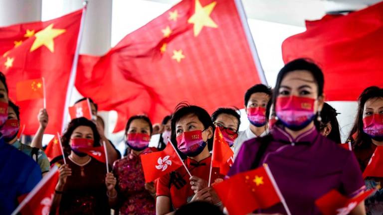 People hold the Hong Kong and Chinese flags while singing to celebrate the 25th anniversary of the city’s handover from Britain to China, in Hong Kong on July 1, 2022. AFPPIX