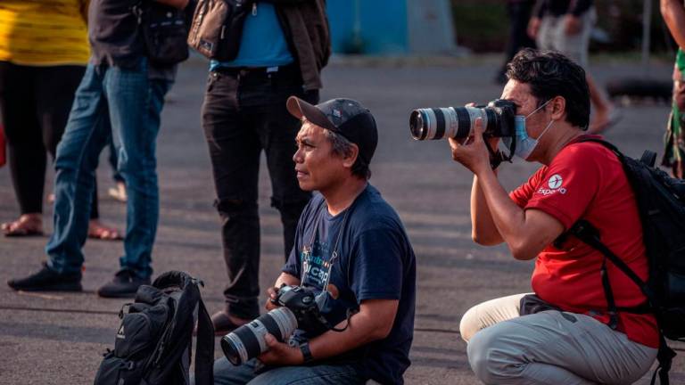 This picture taken on October 4, 2022 shows photographer Ari Bowo Sucipto (L) at work during aftermath coverage of the Kanjuruhan football stadium disaster, in Malang. AFPPIX