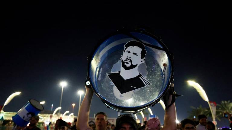 An Argentina fan holds up his drum with an image of Lionel Messi on it on the Doha Corniche/REUTERSPix