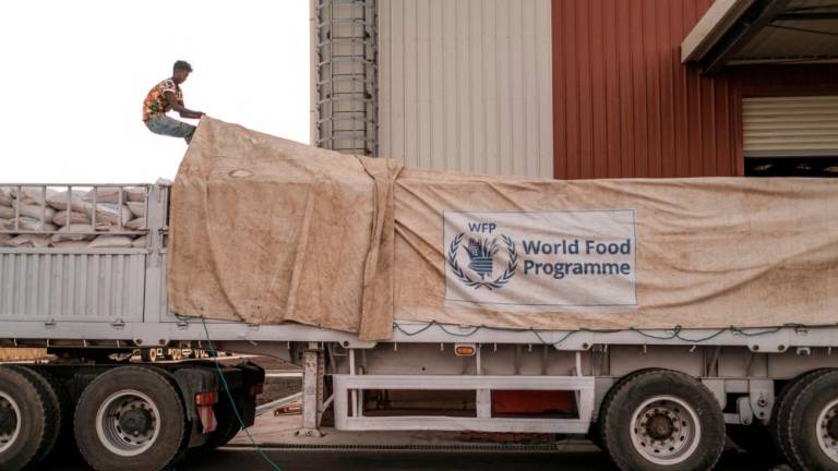 (FILES) In this file photo taken on June 09, 2022 A worker covers a truck full of sacks of grain in a warehouse of the World Food Programme (WFP) in the city of Abala, Ethiopia. AFPPIX