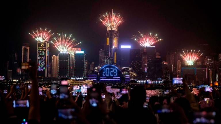 Filepix: Revellers watch a fireworks and laser show as they celebrate the New Year next to Victoria Harbour in Hong Kong on January 1, 2023/AFPPix