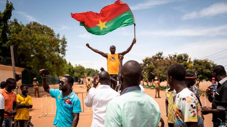 A man waves a Burkina Faso flag as others demonstrate while Burkina Faso soldiers are seen deployed in Ouagadougou on September 30, 2022. AFPPIX